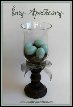 a glass vase filled with blue eggs on top of a wooden stand next to the words easy apothecary