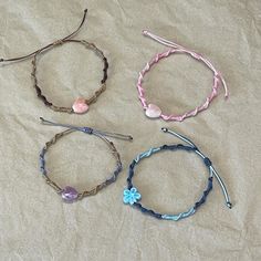 four different bracelets with beads and charms on them sitting on a tablecloth covered surface