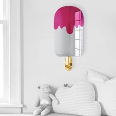 a pink ice cream cone shaped mirror mounted on the wall above a white bed with pillows