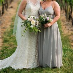 two women standing next to each other in front of some trees and grass with flowers