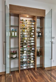 an empty wine cellar with glass shelves filled with bottles and glasses on wooden flooring