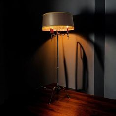 a lamp that is sitting on top of a wooden table next to a black wall