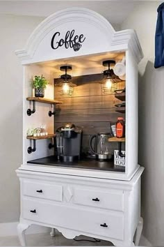 the coffee bar is built into an old dresser with lights on and shelves above it