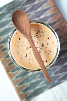 a wooden spoon sitting on top of a glass jar filled with liquid and seasoning