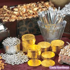 some gold coins are sitting on a table next to a vase with silver foil in it