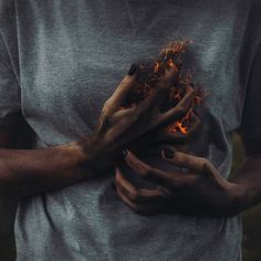 a person holding their hands in front of the camera with flames coming out of them