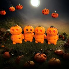 three orange teddy bears sitting in the grass with pumpkins hanging from their heads above them