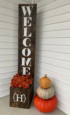 a welcome sign sitting on top of a wooden block next to pumpkins and gourds