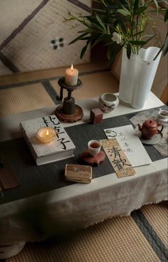 a table topped with candles and books next to a potted plant