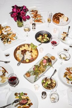 a white table topped with lots of plates filled with food