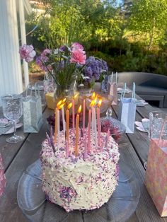 a birthday cake sitting on top of a wooden table with lit candles in the middle