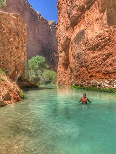 a man wading through the water in a canyon