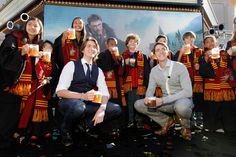 a group of people holding mugs in front of a movie poster with harry potter on it