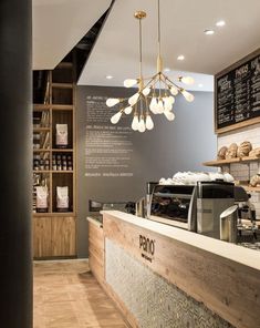 the inside of a coffee shop with wood flooring and counter top, along with shelves full of pastries