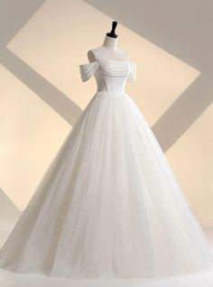 a white wedding dress on a mannequin stand in front of a light box