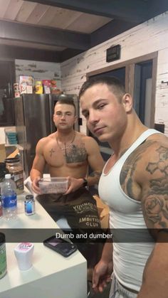 two men standing in a kitchen next to each other with tattoos on their arms and shoulder