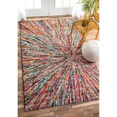 an area rug with multicolored stripes on it and a chair in the background