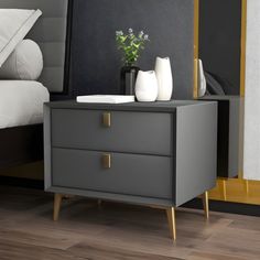 a nightstand with two vases on top of it and a bed in the background