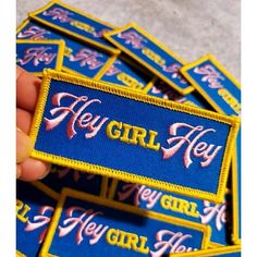 blue and yellow patch with pink lettering that says hey girl on the front in gold letters