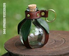 a small glass bottle with a green leaf on it sitting on top of a piece of wood