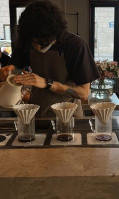 a man with long hair pouring coffee into cups