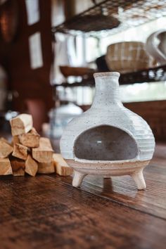 a white vase sitting on top of a wooden table next to cut up pieces of wood