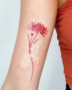 a red and white flower tattoo on the left arm by a woman's arm