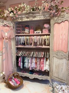 a closet filled with lots of baby clothes next to a basket full of pink flowers