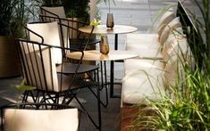 chairs and tables are lined up next to each other on the sidewalk in front of potted plants