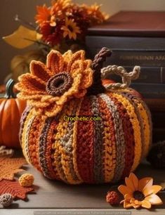 a crocheted pumpkin sitting on top of a table next to books and flowers