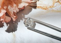 two diamond rings sitting next to each other on top of a white surface with pink flowers in the background