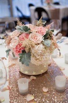 a vase filled with pink and white flowers on top of a table covered in confetti