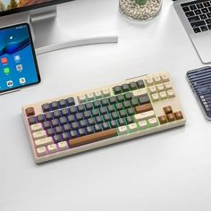 a computer keyboard sitting on top of a white desk next to a phone and tablet