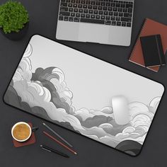 a computer mouse pad with an image of clouds on it next to a cup of coffee