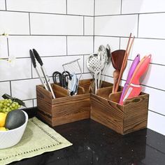 two wooden containers with utensils in them on a counter