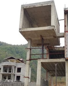 an unfinished concrete building with pipes running from it's roof to the ground below