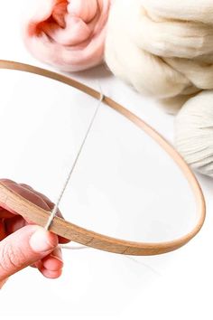 someone is holding a circular piece of wood and threading it with scissors to make a round mirror