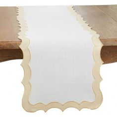 a white table runner with scalloped edges on a wooden table, against a white background