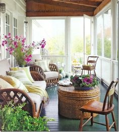 the porch is decorated with wicker furniture and flowers