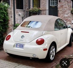 a white car parked in front of a brick building next to a green planter