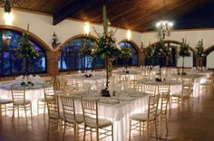 tables and chairs are set up with white linens for a formal function at the lodge