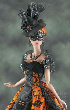 a doll dressed in an orange and black dress with a large hat on her head