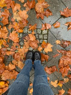 a person standing in front of some leaves on the ground with their legs crossed and feet up