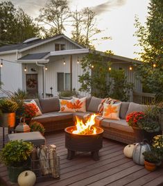 a fire pit sitting on top of a wooden deck surrounded by potted plants and pumpkins