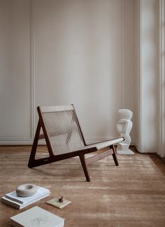 a wooden chair sitting on top of a hard wood floor next to a white vase