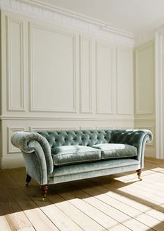 a blue couch sitting on top of a hard wood floor next to a white wall