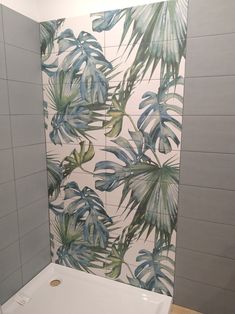 a white bath tub sitting next to a tiled wall