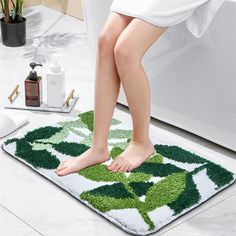 a woman standing on a green and white bathroom rug