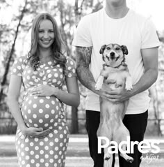 a man and woman standing next to each other holding a dog