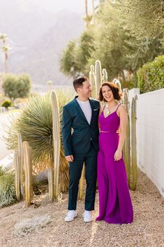 a man and woman standing next to each other in front of cacti